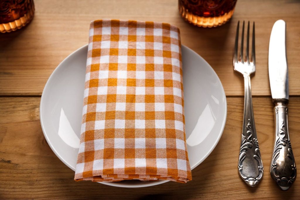 Close-up of a stylish dining table setting with a gingham napkin.