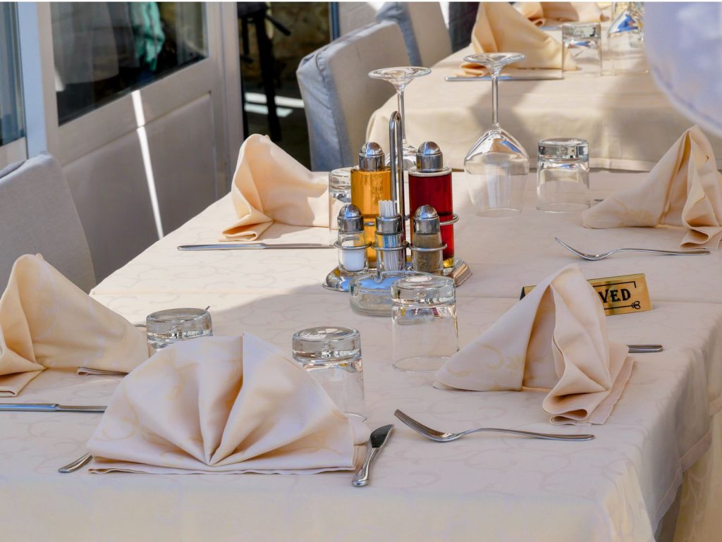 A beautifully arranged outdoor dining table with reserved sign, napkins, and condiments.