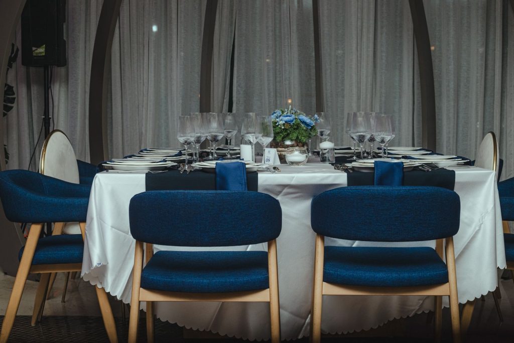 Sophisticated dinner table setup with blue chairs and floral centerpiece, perfect for a formal event.