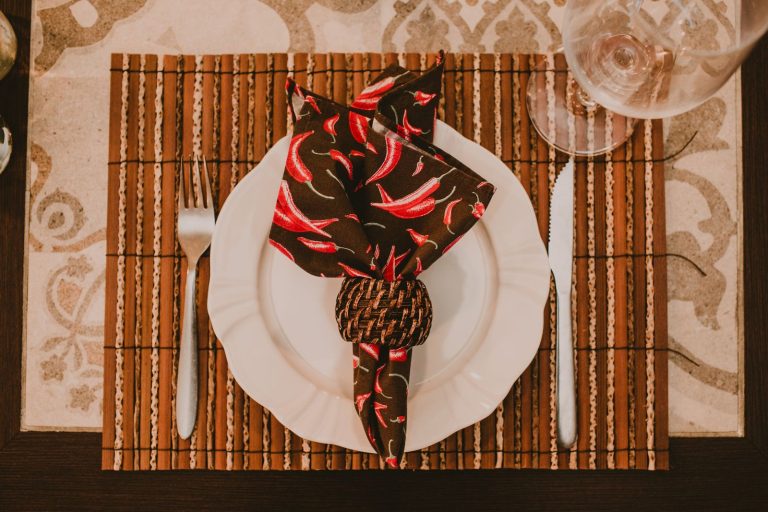 Top view arrangement of banquet setting with brown napkin on plate served on place mat with cutlery and wineglass