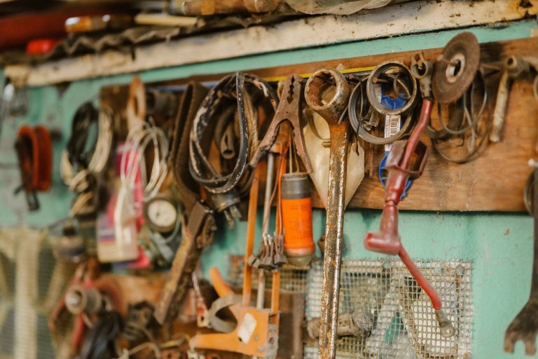 A collection of vintage tools hanging on a workshop wall, showcasing a rustic and messy appeal.