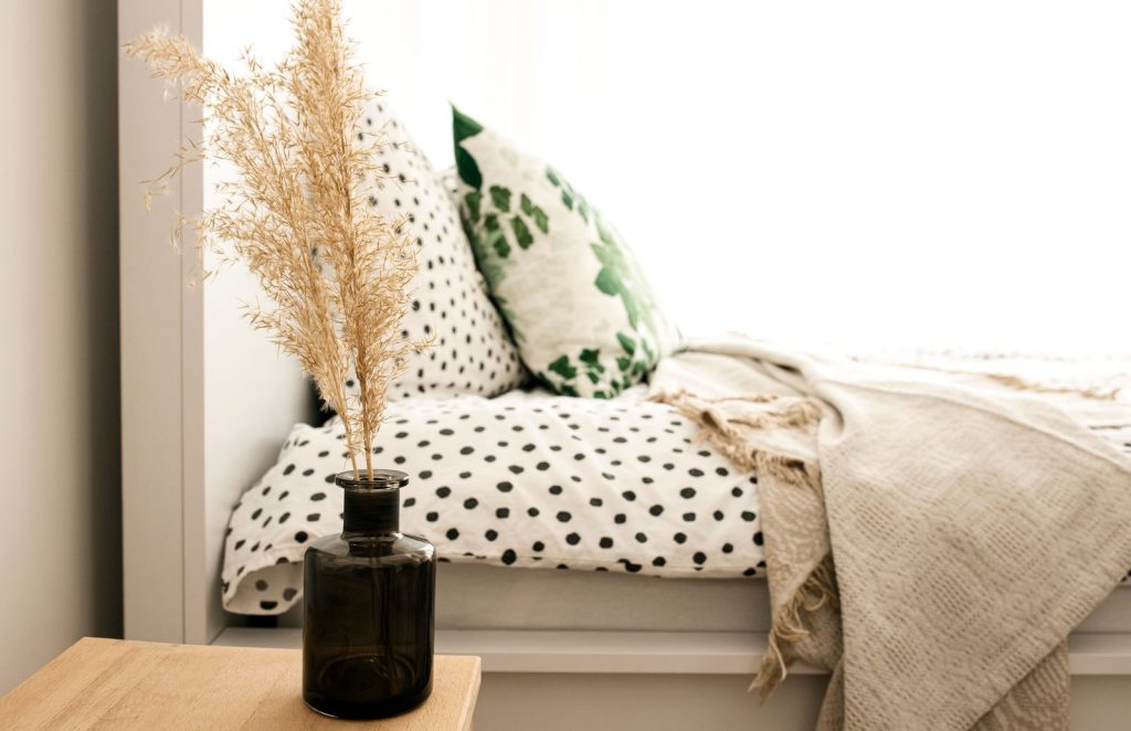 Polka dotted bed with a decorative vase. Cozy and minimalist bedroom decor.