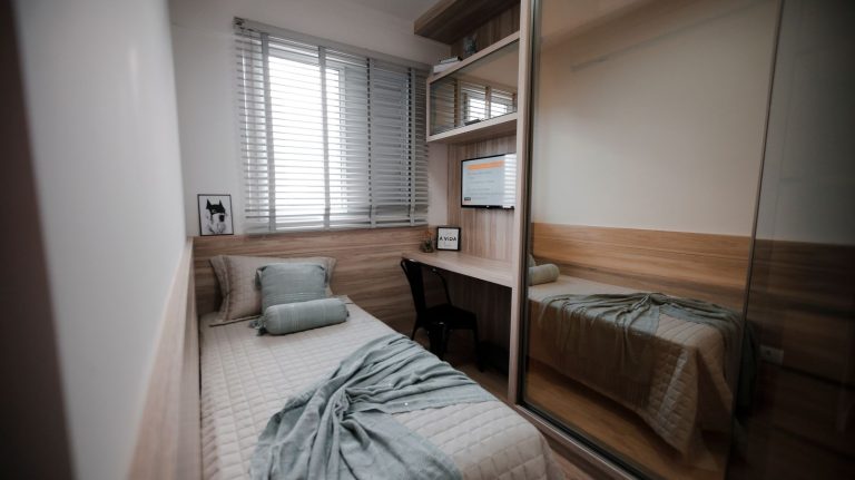 A cozy and minimalist bedroom interior featuring a single bed and a small workspace.