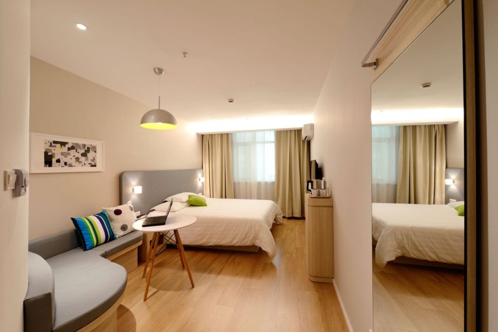 Spacious modern hotel room featuring cozy decor and neutral tones with natural light.