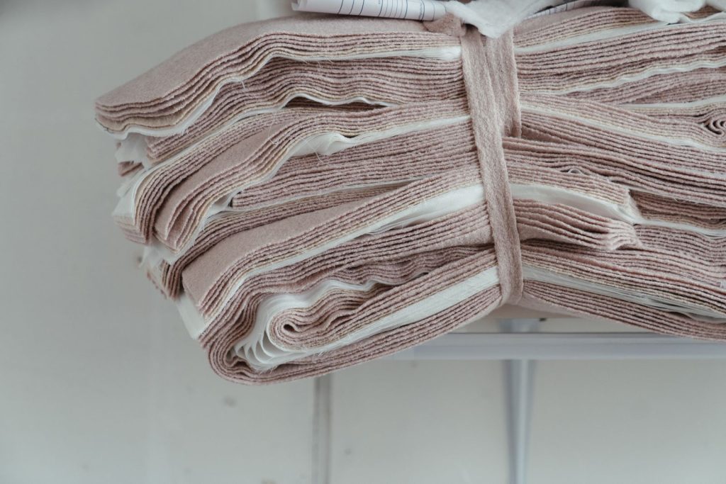 Close-up of neatly stacked pink and white fabric in a sewing workshop, ideal for fashion designs.