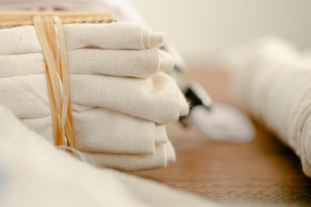 Various ecologically friendly cotton sacks with drawstrings placed on wooden table in light room