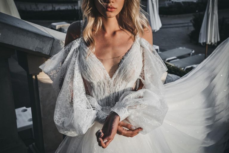 A beautiful bride in an elegant lace wedding dress standing outdoors, exuding grace and style.