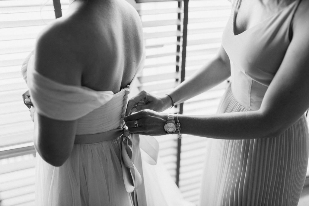 Intimate black and white shot of wedding preparation with bride and bridesmaid.