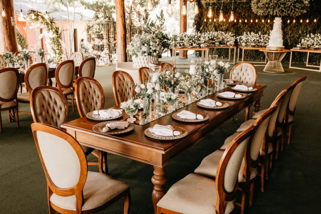 A beautifully decorated wedding venue with elegant table settings, chairs, and floral arrangements.