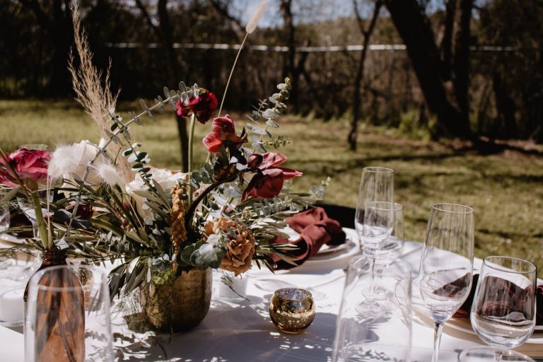 Beautiful outdoor table setting with elegant floral arrangement and glassware, perfect for gatherings.