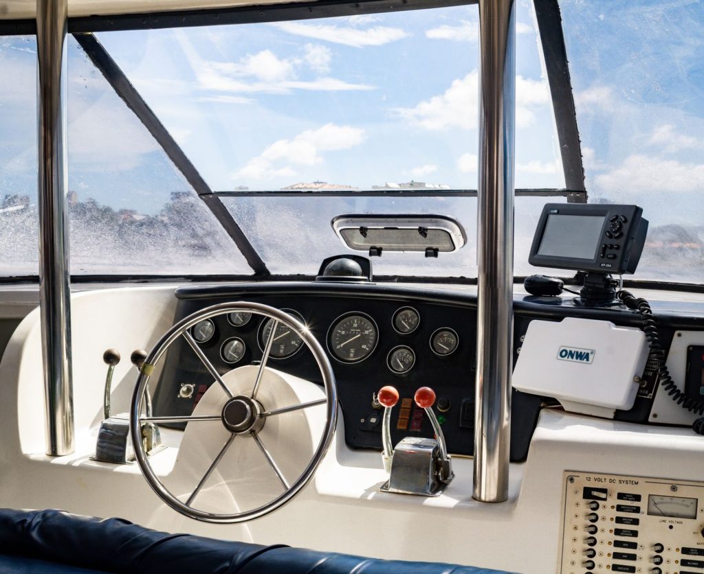 Close-up view of a ship's cockpit showcasing navigational equipment and a steering wheel.