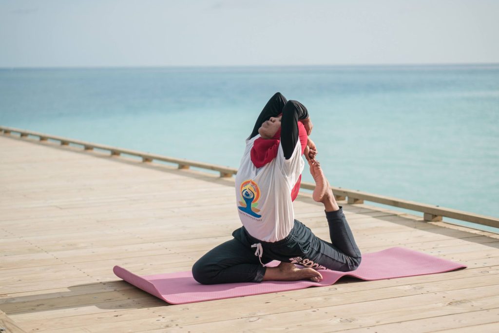 Woman practicing yoga on a wooden dock by the sea, enjoying the peaceful ocean view.