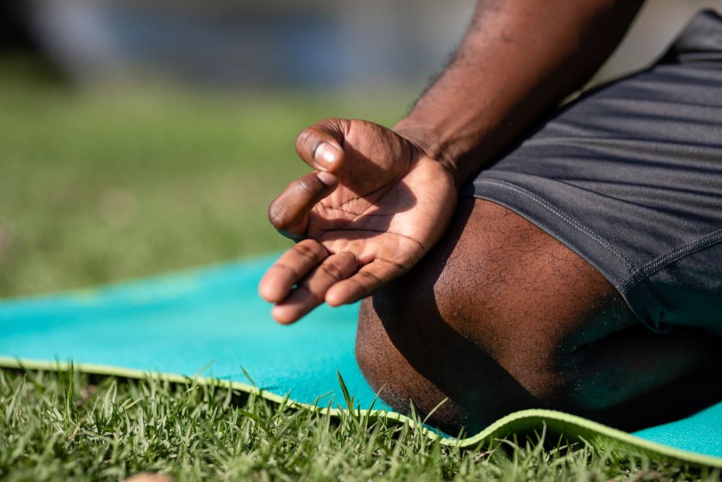 Focused meditation hand gesture on a blue yoga mat outdoors, highlighting mindfulness.