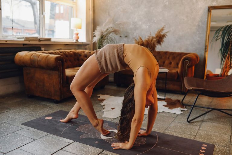 Flexible woman performing yoga wheel pose in a cozy indoor setting.