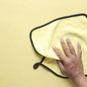 Hand holding a yellow microfiber towel