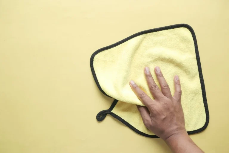 Hand holding a yellow microfiber towel