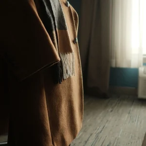 Stylish camel coat draped over chair in cozy room