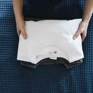 Neatly folded white crew neck t shirt over other shirts