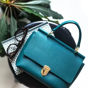 Stylish handbag on stool in light room