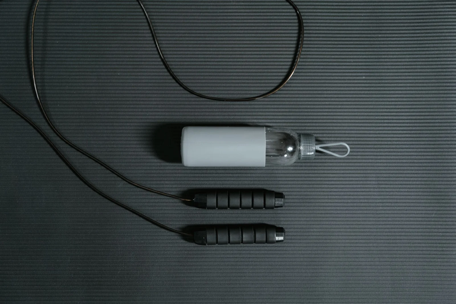 Jump rope and water bottle arranged on a yoga mat